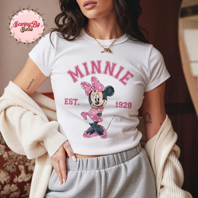 A woman wearing a white t-shirt with a Minnie Mouse graphic and the text "MINNIE EST. 1928" printed on it.