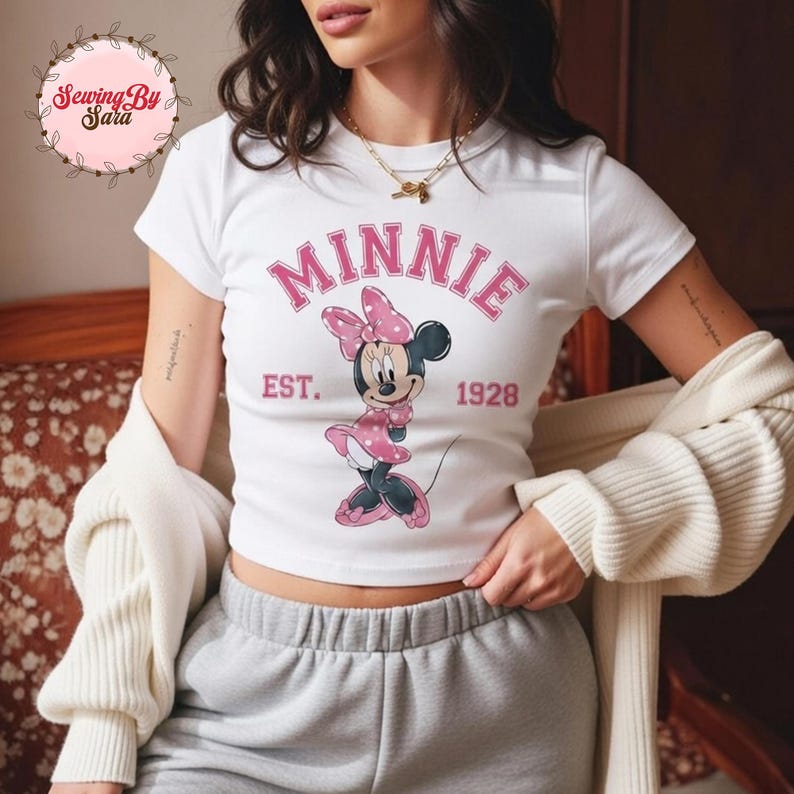 A woman wearing a white t-shirt with a Minnie Mouse graphic and the text "MINNIE EST. 1928" printed on it.