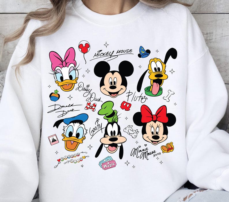 A white sweatshirt with various Disney characters and their signatures printed on it.