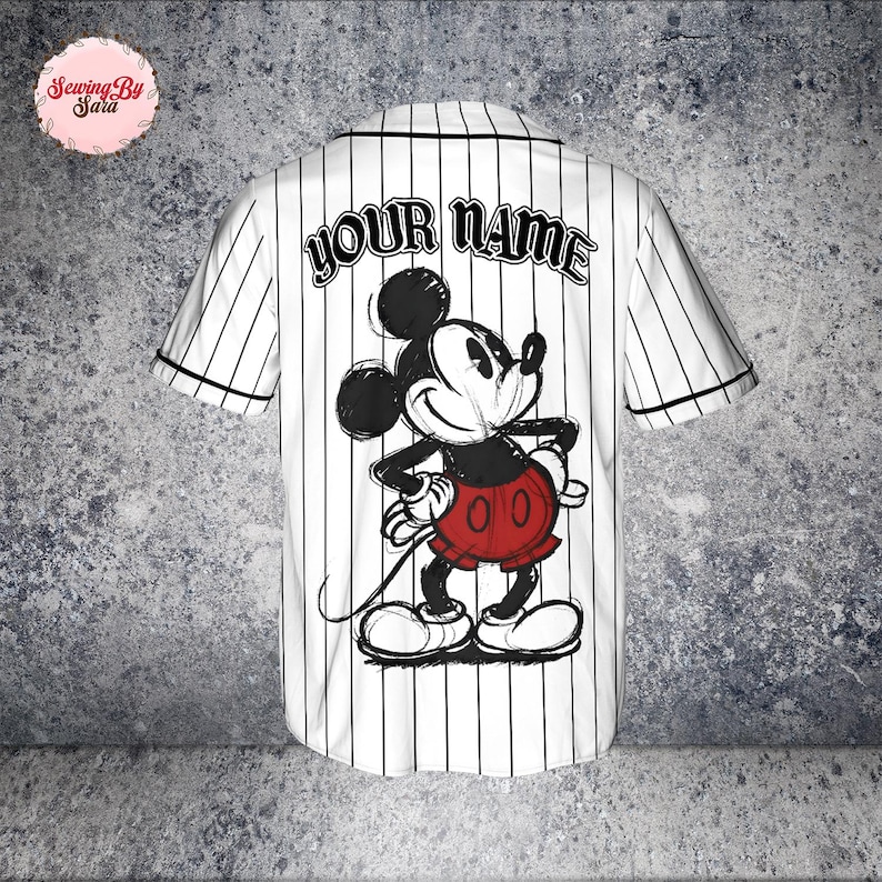 A white baseball jersey with a Mickey Mouse design and the text "YOUR NAME" printed on the back.