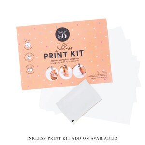May include: A pink and white card with the words 'Baby Ink' and 'Inkless Print Kit' in black text. The card has a picture of a baby's foot and the words 'capture a precious keepsake magically with no messy ink!' The card also has three steps for using the kit. The card is surrounded by white paper and a white envelope.