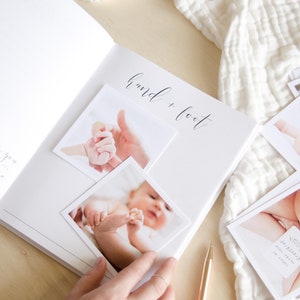 May include: A white baby memory book with the words 'hand + foot' written in black ink. The book has two pages open, and there are three photos of a baby's hand and foot. The photos are placed on the page with the words 'hand + foot'.