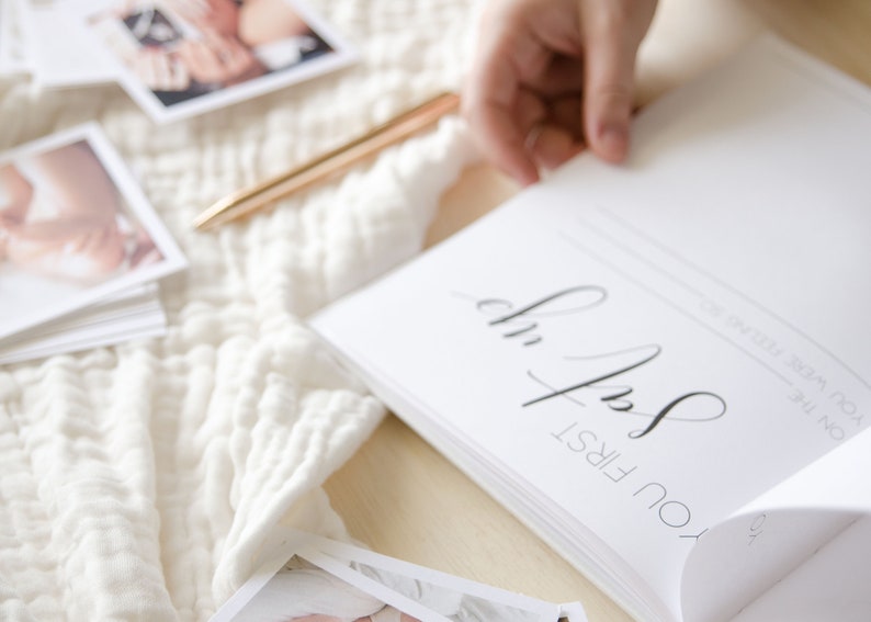 May include: A white, blank, hardcover book with the text 'You First' in black calligraphy on the front cover. The book is open to a blank page with the text 'On the first year of your life' in black text.