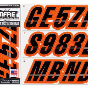 May include: Stiffie 3-inch alphanumeric registration decals for boats and personal watercraft. The set features black characters with orange outlines and a horizontal grey stripe. The packaging displays the Stiffie logo, Made in U.S.A. text, and the characters GE5ZI, S983L, MBND, and 46574.