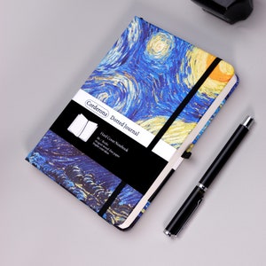 Puede incluir: Un diario punteado azul y amarillo con una cubierta dura que presenta una pintura de una noche estrellada. El diario tiene un cierre elástico negro y una etiqueta en blanco y negro que dice "Corderona Dotted Journal Hard Cover Notebook B6/Boshs shogsn wood-free paper inspire your ideas".