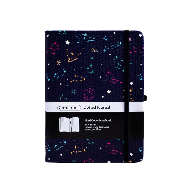 May include: A blue hard cover dotted journal with a constellation pattern. The journal has a black elastic closure and a white label that reads "Corderona Dotted Journal". The label also includes the text "Hard Cover Notebook", "B6/Boshs", "160gsm wood-free paper", and "Inspire your ideas".