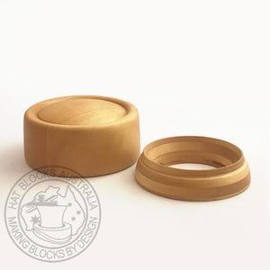Op de afbeelding: Tweedelige hoedenblokset van lichtgekleurd hout. De set bevat een afgeronde, cilindrische basis en een apart, ringvormig onderdeel. Het logo aan de linkerkant luidt "HAT BLOCKS AUSTRALIA MAKING BLOCKS BY DESIGN."