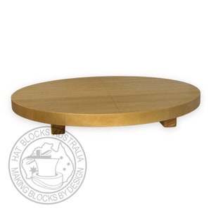 May include: A round wooden cake stand with a natural wood finish and four small legs. The stand is made of two pieces of wood that are joined together in the center.