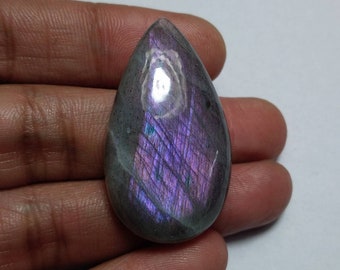 May include: A teardrop-shaped, iridescent labradorite gemstone with a purple and gray color scheme. The stone has a smooth, polished surface and displays a shimmering effect.
