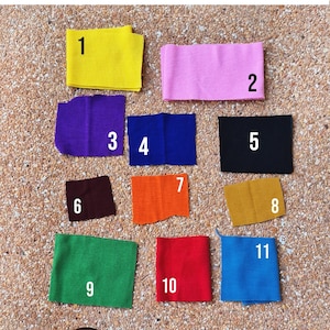 May include: Twelve fabric swatches in different colors, numbered 1 through 12. The swatches are arranged in a grid pattern on a textured surface.  Choose Your Ringer.