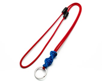 Könnte beinhalten: Ein rotes Lanyard mit einem blauen Paracord-Knoten und einem silbernen Schlüsselring.