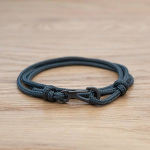 Könnte beinhalten: Ein dunkelgraues Seil-Armband mit einem schwarzen Metallverschluss.