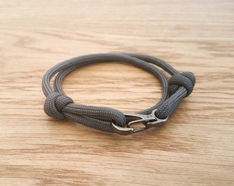 May include: A gray paracord bracelet with a black metal clasp.
