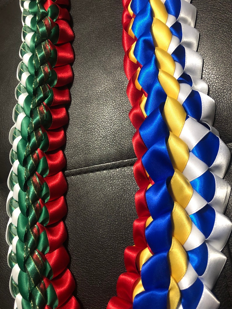 以下が含まれることがあります： 赤、緑、白のリボンと、青、黄、白のリボンでできた、手作りのレイ2つ