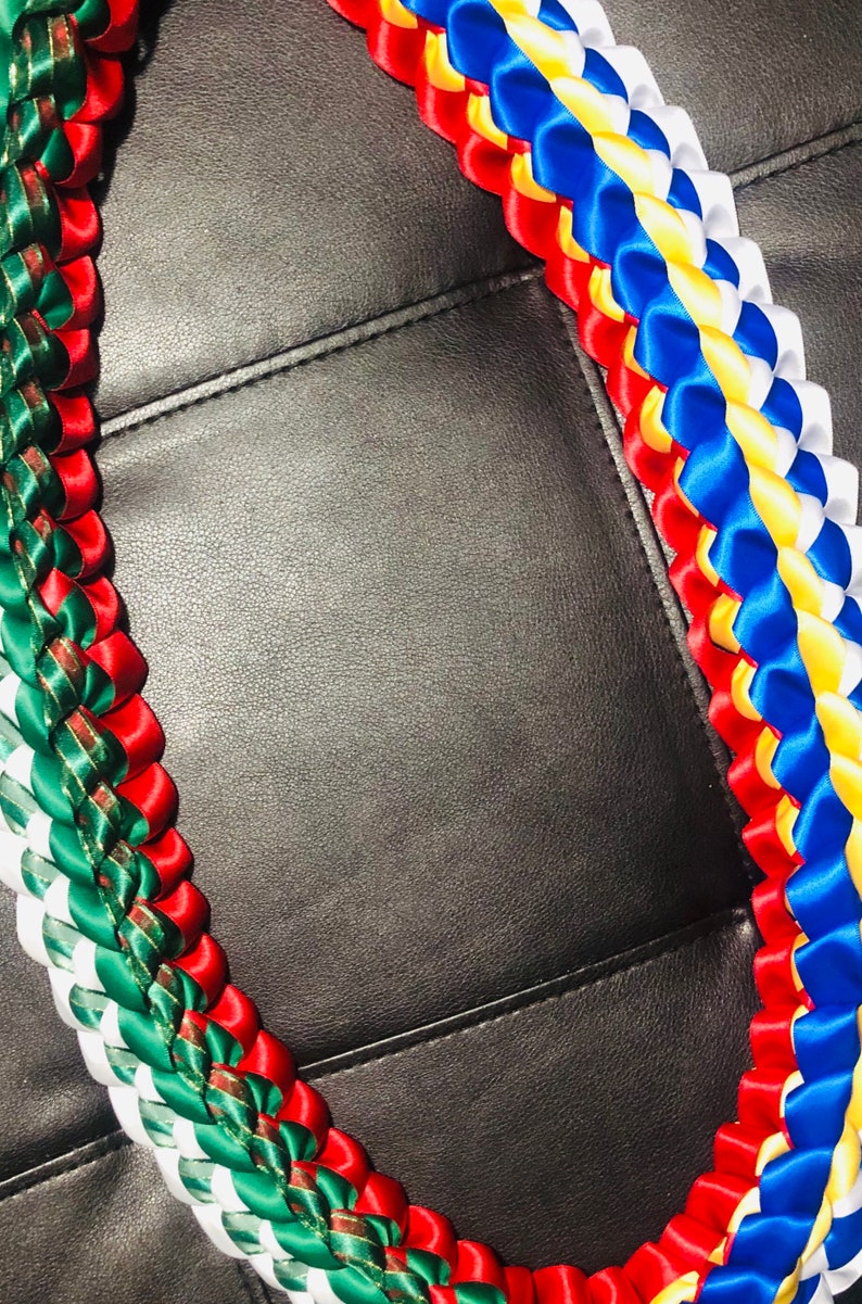 以下が含まれることがあります： 赤、白、緑、青、黄色のサテンリボンを編んだ伝統的なハワイのレイです。