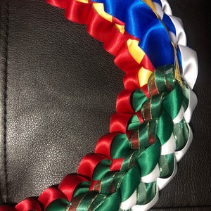 以下が含まれることがあります： サテンリボンでできたマルチカラーのレイ。レイは赤、白、青、黄、緑のリボンで作られています。リボンは美しく複雑なデザインを作り出すために織り込まれています。