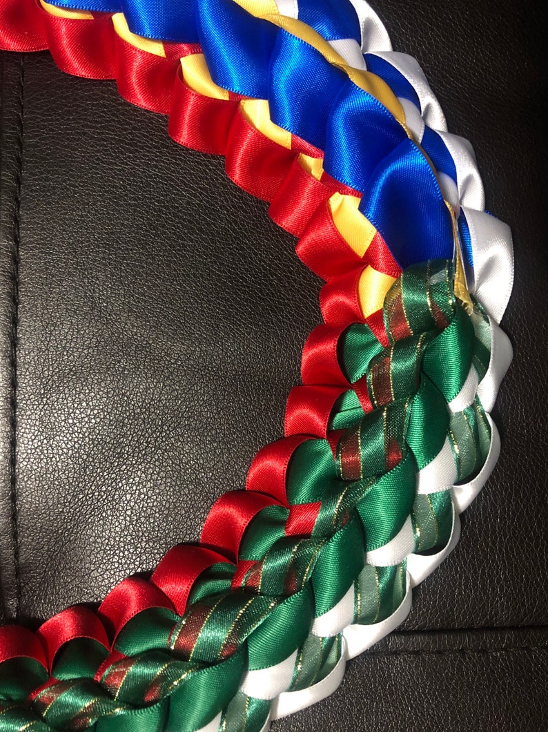以下が含まれることがあります： サテンリボンでできたマルチカラーのレイ。レイは赤、白、青、黄、緑のリボンで作られています。リボンは美しく複雑なデザインを作り出すために織り込まれています。