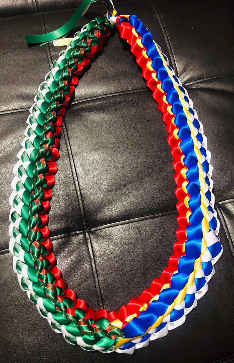 以下が含まれることがあります： 赤、白、青、緑、金色のサテンリボンを織り込んだ伝統的なハワイのレイです。