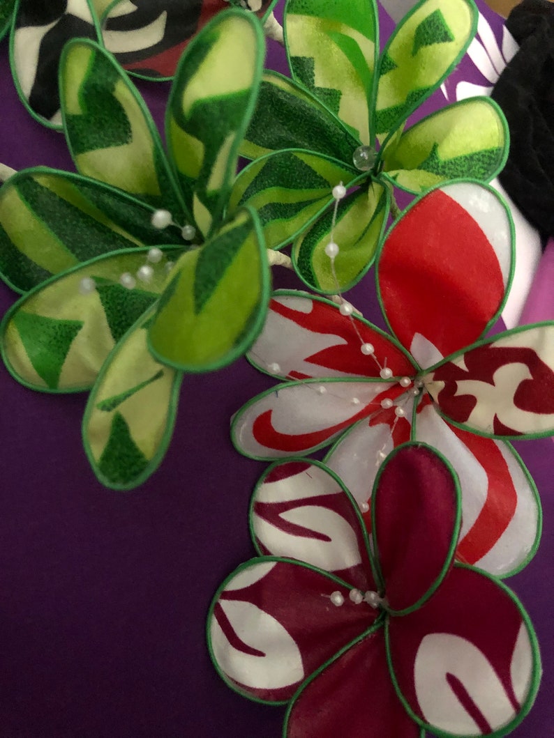 Puede incluir: Primer plano de una tela morada con un dise&ntilde;o floral. Las flores est&aacute;n hechas de tela y tienen colores verde, rojo, blanco y burdeos. Las flores est&aacute;n decoradas con cuentas blancas.
