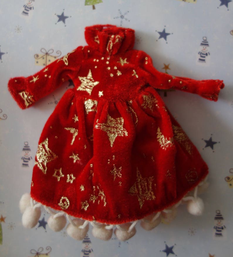 Puede incluir: Vestido de mu&ntilde;eca de terciopelo rojo con patrones de estrellas y puntos dorados. El vestido tiene mangas largas, cuello alto y falda con ribete de pomp&oacute;n blanco. El vestido mide aproximadamente 25 cm de largo.