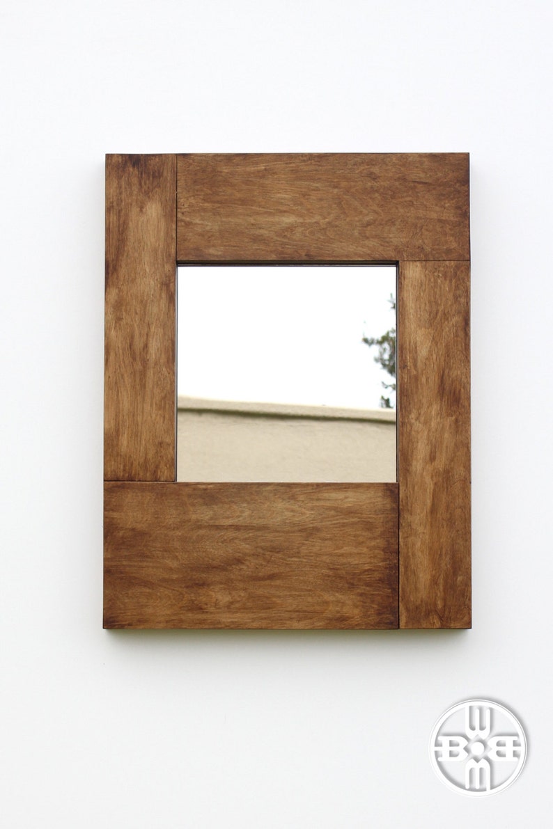 Puede incluir: Un espejo rectangular de madera con un acabado de tinte marr&oacute;n. El espejo tiene un marco simple con un borde ligeramente elevado.