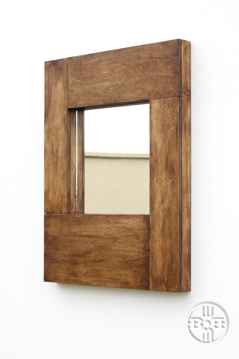 Puede incluir: Un espejo rectangular de madera con un acabado de tinte marr&oacute;n. El espejo tiene un marco simple con un borde ligeramente elevado.