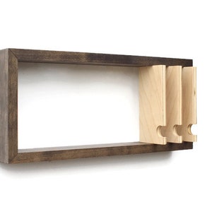 May include: A dark brown wooden wall shelf with three light wood shelves that have a unique cut-out design. The shelves are attached to the wall with screws.