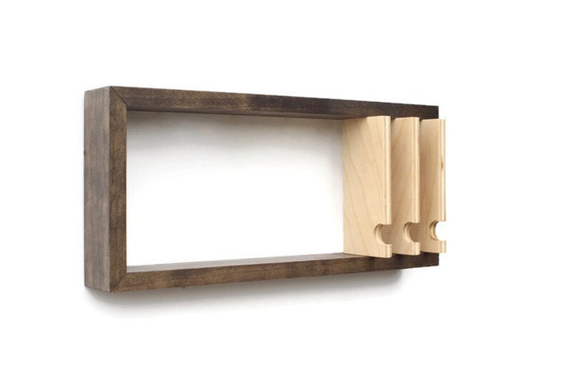 May include: A dark brown wooden wall shelf with three light wood shelves that have a unique cut-out design. The shelves are attached to the wall with screws.