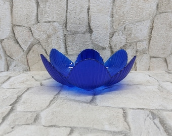 May include: A blue glass bowl shaped like a flower with five petals.
