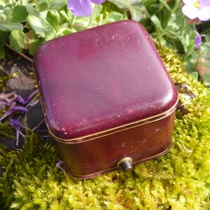 Piccola scatola porta-anelli antica, parte superiore in pelle rossa, bordi dorati e interno in velluto nero e seta beige, circa 1900-20
