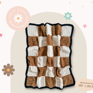 May include: A handmade, checkerboard-patterned blanket in shades of brown and white, with a dark blue border. The blanket measures 39 inches by 30.5 inches. The text on the image reads "ONE OF A KIND HEIRLOOM BLANKET."