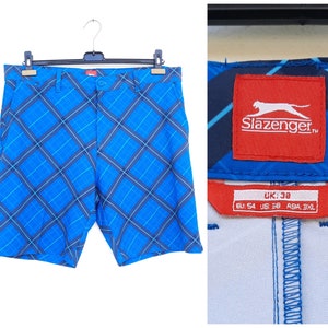 May include: Blue and black plaid shorts with a red label that says "Slazenger" and size information. The label also includes the size conversions for EU, US, and Asia.