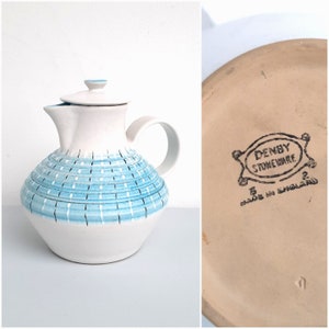 May include: White teapot with a blue and white geometric pattern. The teapot has a lid and a handle. The bottom of the teapot has a brown stamp that reads "DENBY STONEWARE MADE IN ENGLAND".