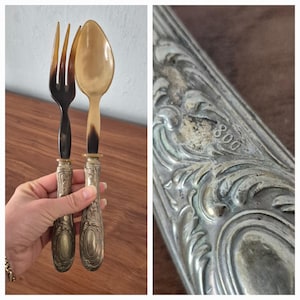 May include: A set of antique silver-plated salad servers with horn handles. The handles are a dark brown colour and the silver is tarnished. The servers are in a silver case with the number 800 stamped on it.