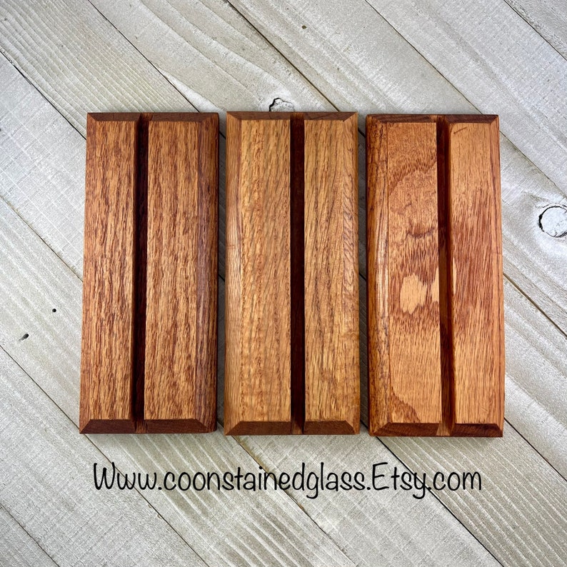 Op de afbeelding: Drie rechthoekige houten displaystandaards met een verticale groef. De standaards zijn gemaakt van roodbruin hout met zichtbare nerf. Het websiteadres "www.coonstainedglass.etsy.com" staat onderaan afgedrukt.