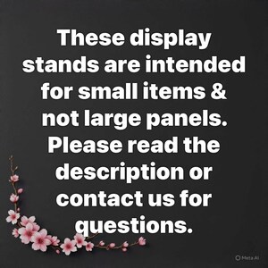 Op de afbeelding: Zwarte achtergrond met witte tekst die aangeeft dat display stands bedoeld zijn voor kleine items, niet voor grote panelen. De tekst zegt ook dat je de beschrijving moet lezen of contact moet opnemen voor vragen. Een bloemenontwerp met roze bloemen staat in de linker benedenhoek.
