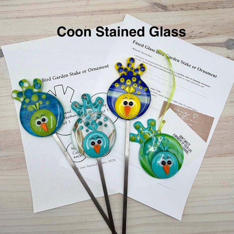 May include: Four colorful fused glass bird garden stakes or ornaments. Each bird has a unique design with blue, green, and yellow accents. The text "Coon Stained Glass" and "Bird Garden Stake or Ornament" are visible.