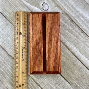 K&ouml;nnte beinhalten: Ein rechteckiger Holzgegenstand mit einer vertikalen Nut in der Mitte. Das Holz hat einen rotbraunen Farbton und ein sichtbares Maserungsmuster. Ein Lineal liegt daneben und misst etwa 13 cm.