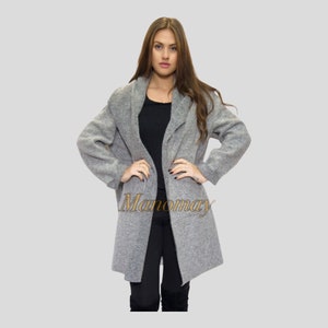May include: A grey long-sleeved cardigan with a shawl collar. The cardigan is open at the front and has a relaxed fit.