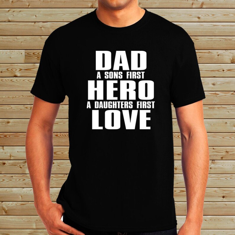 Puede incluir: Camiseta negra con texto blanco que dice "Dad A Sons First Hero A Daughters First Love"