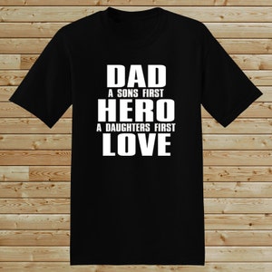 Puede incluir: Camiseta negra con texto blanco que dice "Dad A Sons First Hero A Daughters First Love"