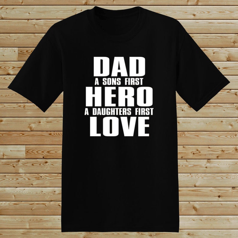 Puede incluir: Camiseta negra con texto blanco que dice "Dad A Sons First Hero A Daughters First Love"