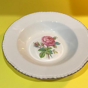 May include: White ceramic soup bowl with a gold rim and a pink rose floral design.