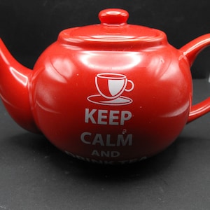 Könnte beinhalten: Rote Keramik-Teekanne mit einem weißen Design, auf dem "Keep Calm and Drink Tea" steht.