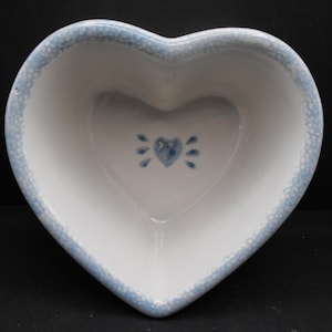 May include: A white heart-shaped ceramic bowl with a blue rim and a blue heart design in the centre.