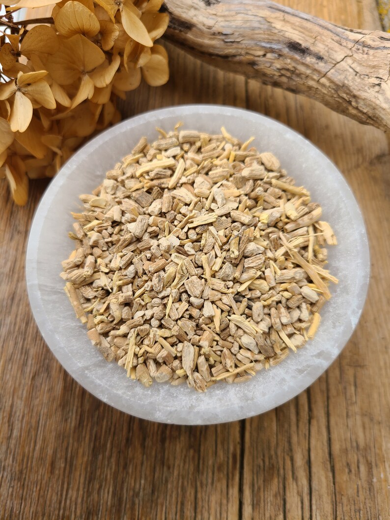 May include: A white bowl filled with dried, light brown, and beige root pieces. The bowl is sitting on a wooden surface.