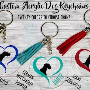 Può includere: Quattro portachiavi personalizzati per cani in acrilico con un design a forma di cuore e una silhouette di cane. I portachiavi sono blu, turchese, rossi e trasparenti con un cuore rosso. Ogni portachiavi ha un anello portachiavi argentato e un fiocco. Il testo sui portachiavi è "German Shorthaired Pointer", "German Wirehaired Pointer", "Bailey" e "Giant Schnauzer".