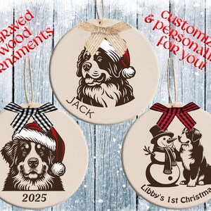 May include: Three engraved wood ornaments with dog illustrations. Each ornament is round and beige, featuring a dog wearing a Santa hat or with a snowman. Text includes names and the year 2025. Bows in various patterns adorn the tops.