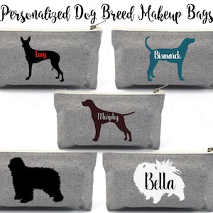 Può includere: Borse per il trucco in tela grigia con sagome di varie razze di cani e nomi. Le borse presentano illustrazioni di cani neri, verde acqua e marrone con nomi come "Lucy", "Bismarck", "Murphy" e "Bella". Il testo "Personalized Dog Breed Makeup Bags" è in alto.