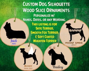 Puede incluir: Cuatro adornos redondos de madera con siluetas de perros. Los adornos están personalizados con nombres y fechas. Las razas de perros son Skye Terrier, Smooth Fox Terrier, Soft Coated Wheaten Terrier y un terrier mixto. El texto en los adornos dice "Jack 2017", "Sammy Feliz Navidad 2017", "Buddy 2004-2017" y "Bailey".